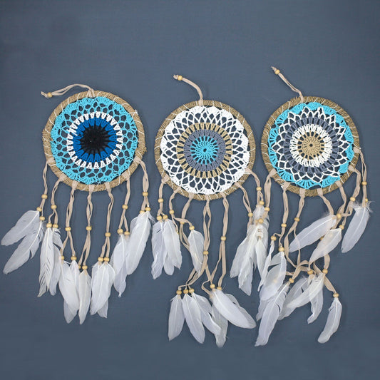 Small pastel blue macramé dream catcher with intricate hand-woven webbing and hanging cotton tassels.