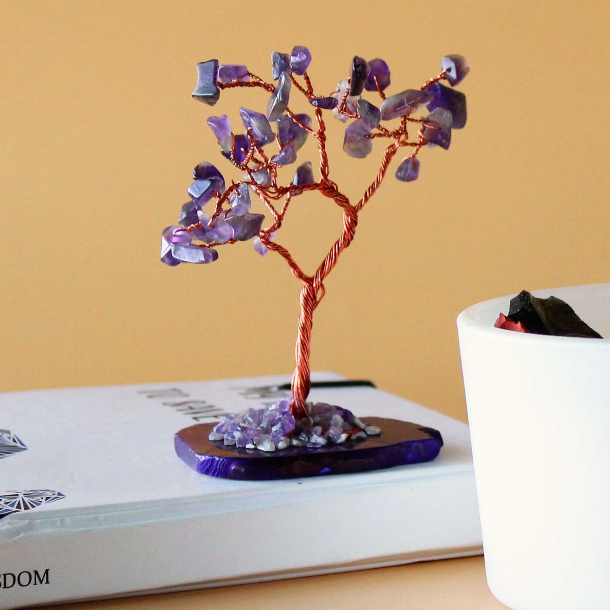 Handcrafted gemstone tree with purple amethyst leaves on a wire trunk and a natural polished agate slice base.