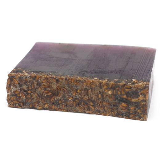 Hand-crafted purple soap slice topped with dried lavender flowers, wrapped in traditional waxed paper.