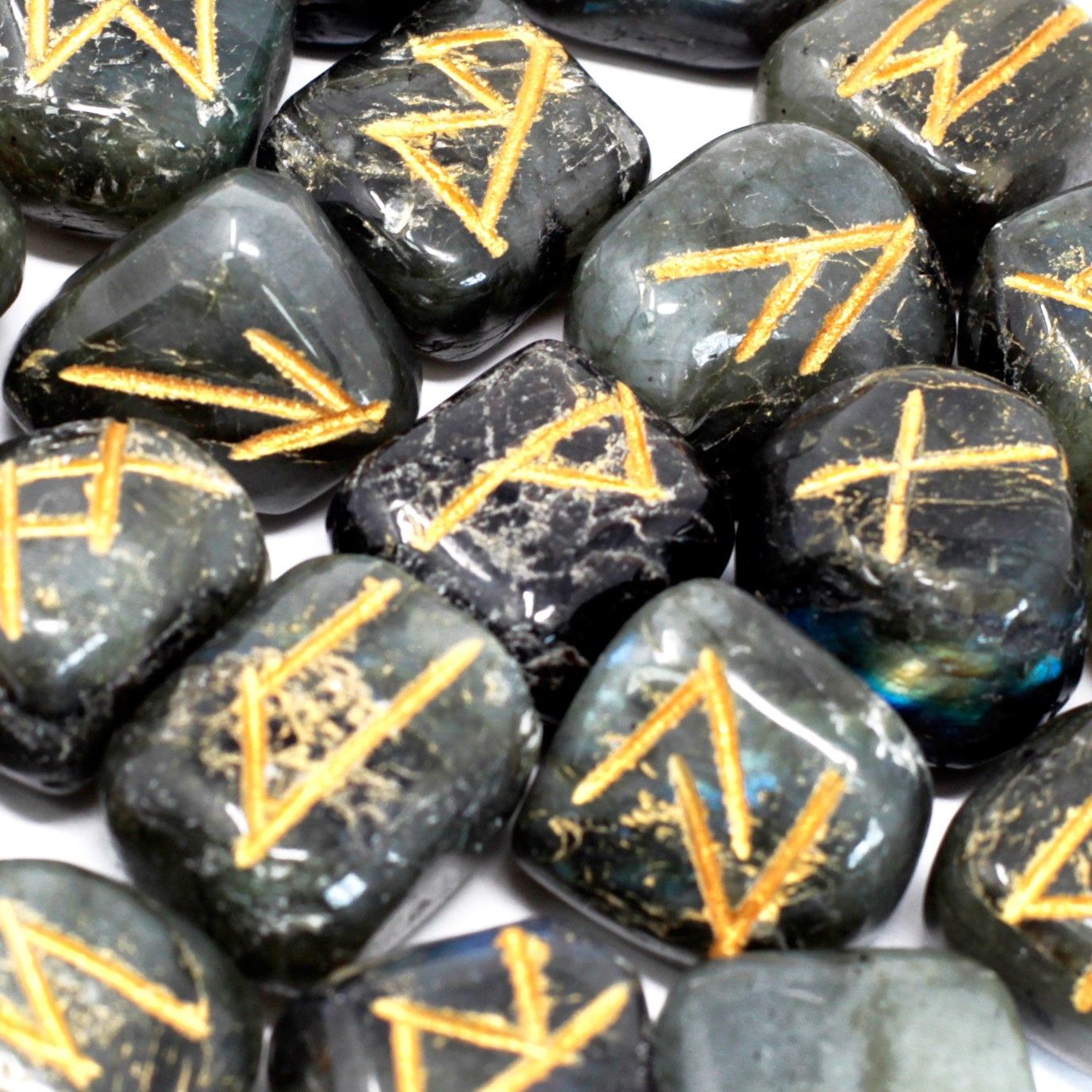 Set of iridescent Labradorite stones engraved with silver rune symbols resting inside a small black fabric drawstring pouch.
