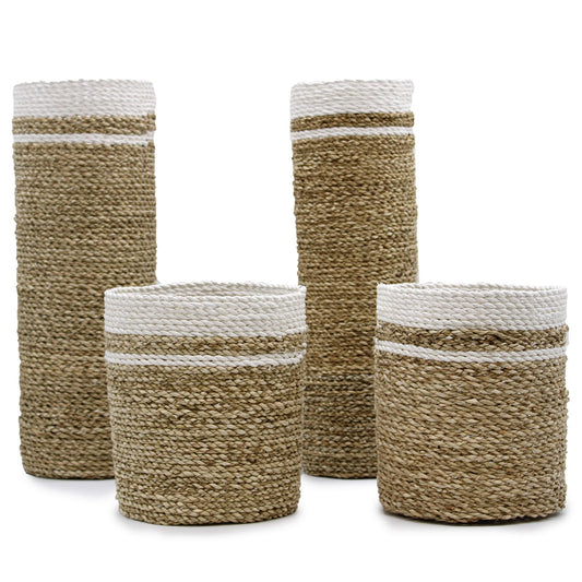 Four piece woven seagrass set including two tall cylindrical vases and two round storage bins in a natural finish.