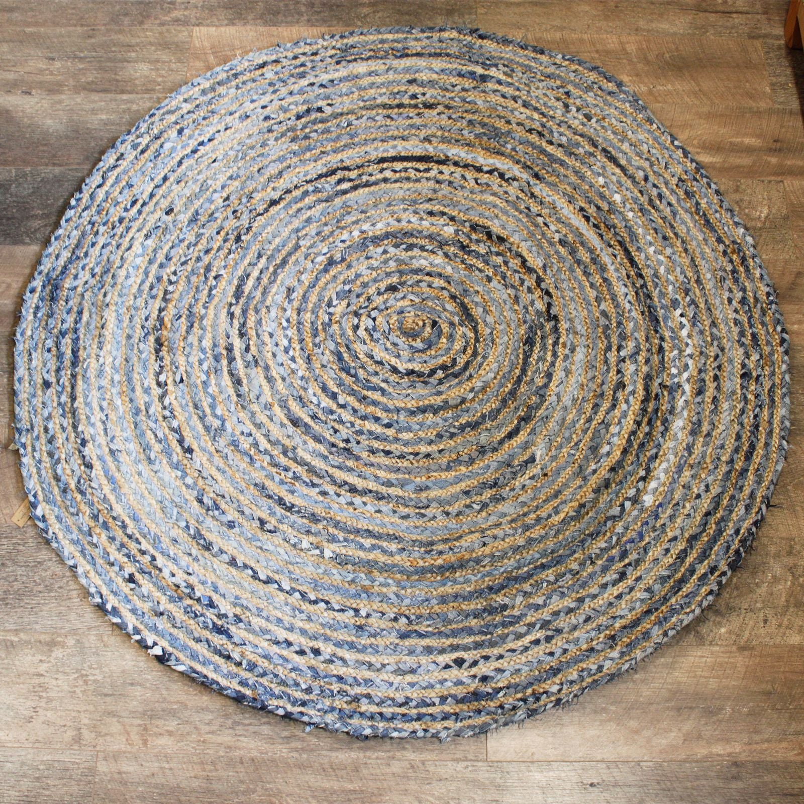 Large round hand-woven rug made from natural jute and blue recycled denim off-cuts in a spiral pattern.