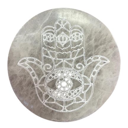 Round white selenite charging plate engraved with a symbolic Hamsa hand design for spiritual crystal cleansing.