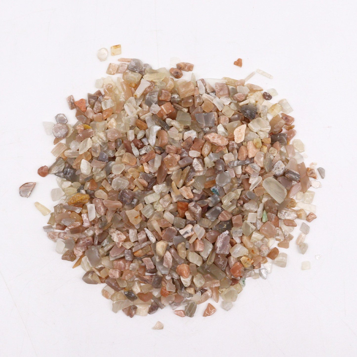 A large pile of small, shimmering white and translucent moonstone gemstone chips in a bulk one kilogram quantity.