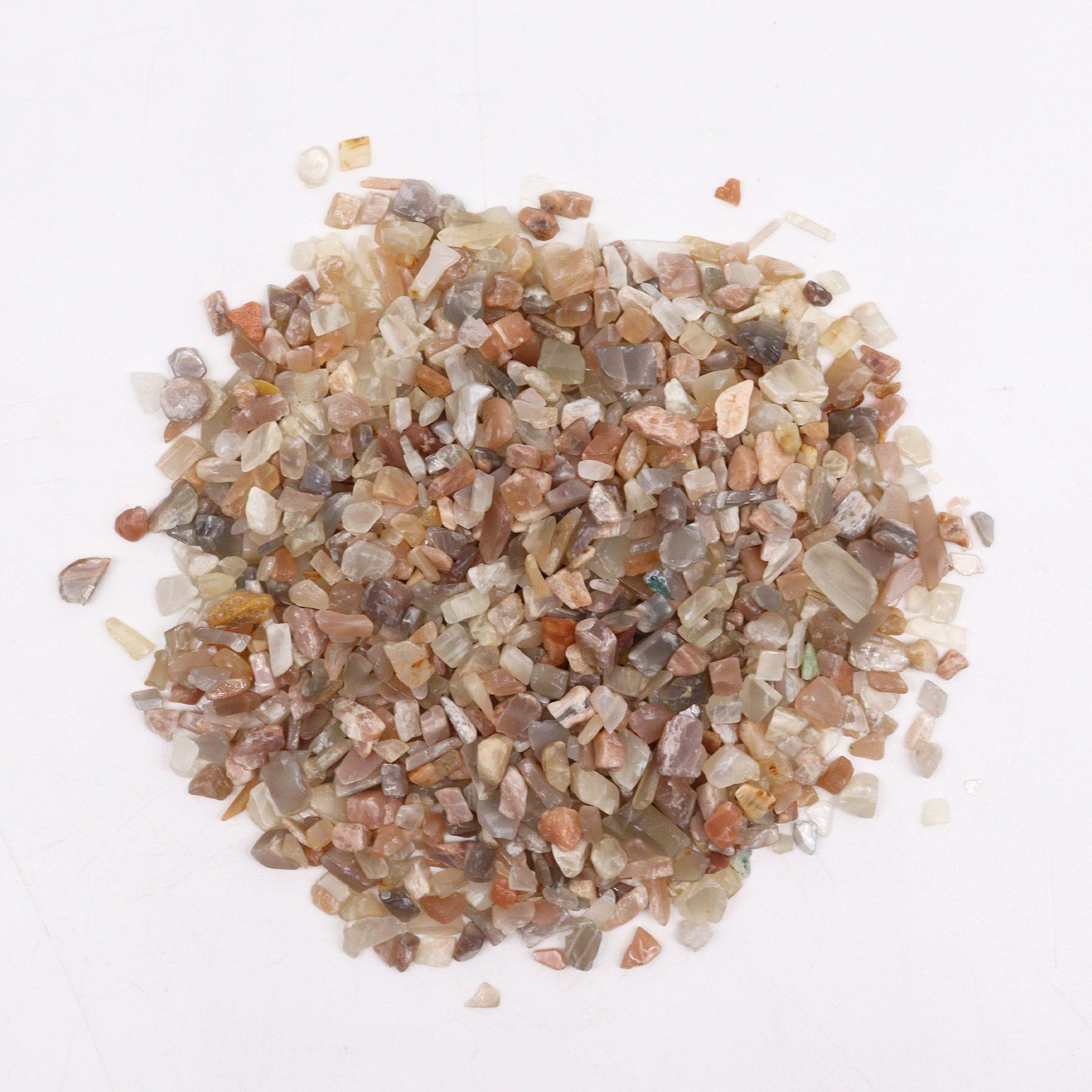 A large pile of small, shimmering white and translucent moonstone gemstone chips in a bulk one kilogram quantity.