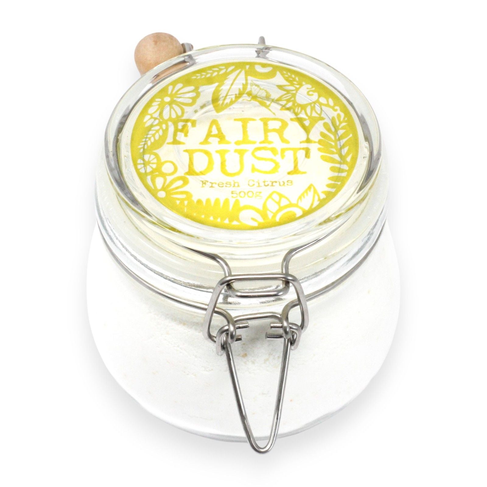 Fine zesty orange and yellow bath dust in a glass jar with a wooden scoop on a white surface.