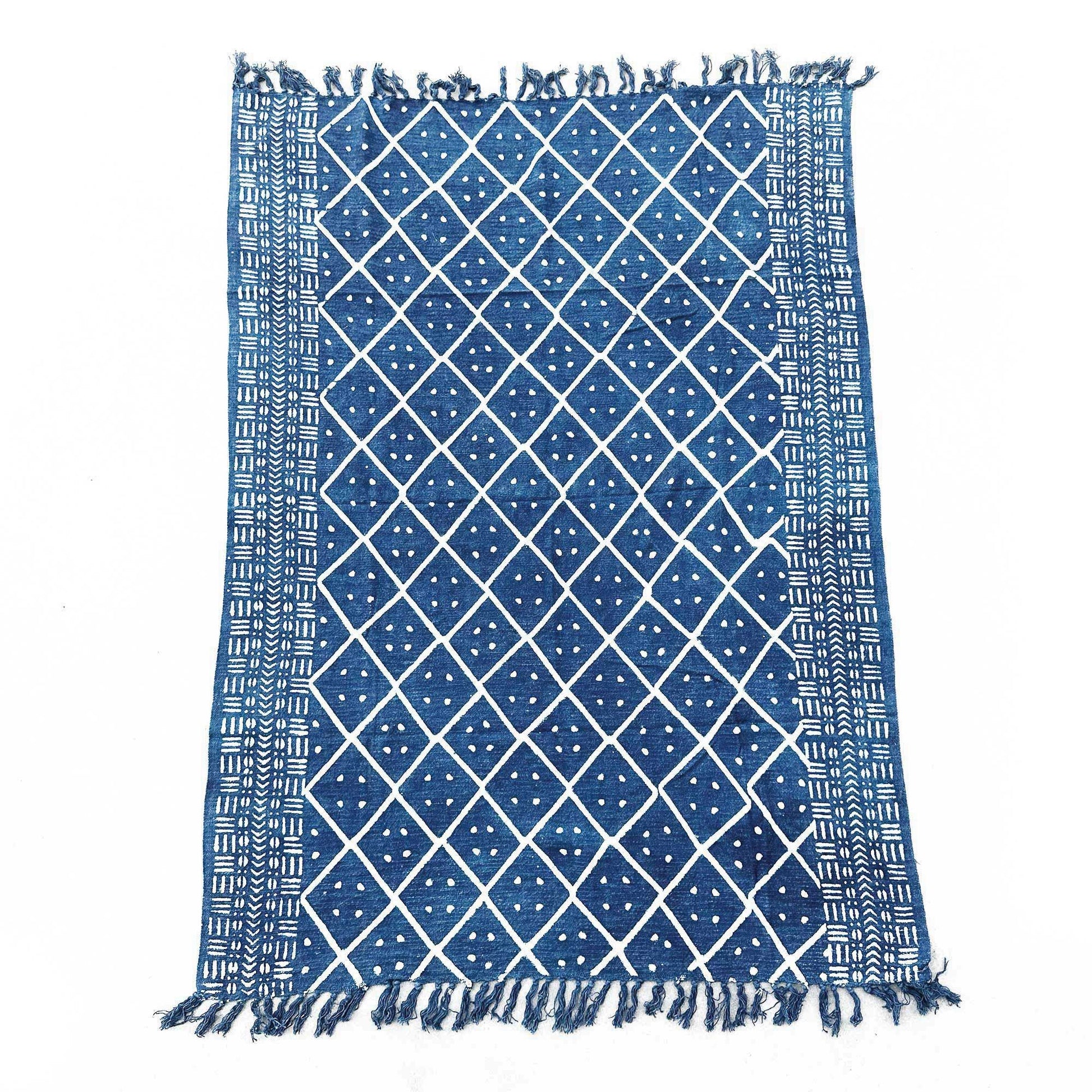 Close-up of a handmade indigo throw featuring an intricate white Midnight Heerak geometric pattern with fringed edges.