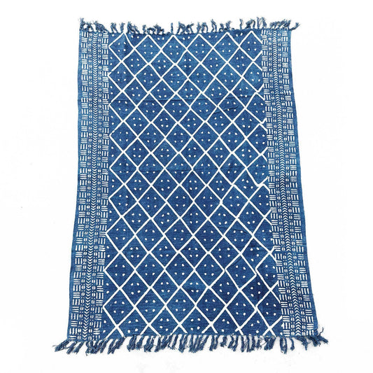 Close-up of a handmade indigo throw featuring an intricate white Midnight Heerak geometric pattern with fringed edges.