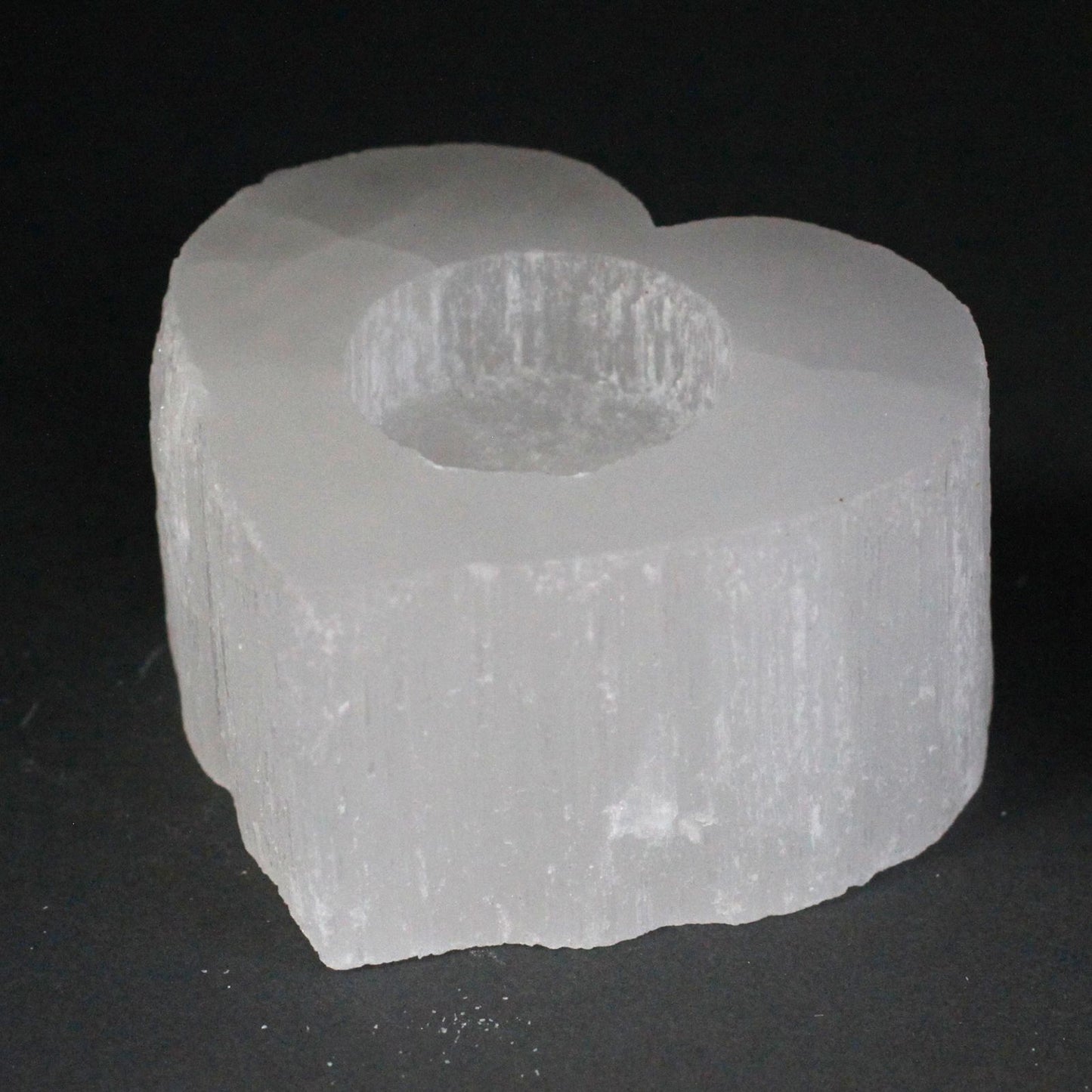 Heart-shaped selenite candle holder with a natural rough edge and a translucent white crystal finish.