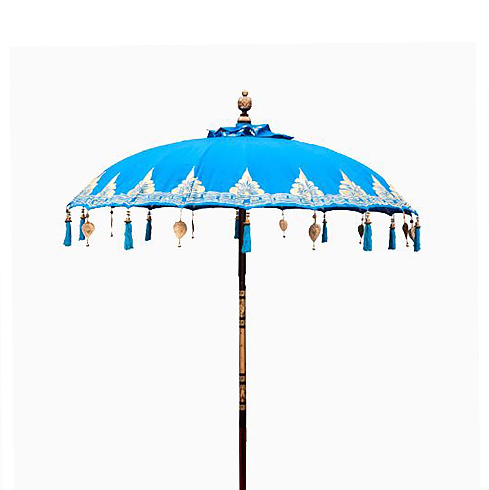 Beautiful turquoise cotton patio parasol with intricate Balinese patterns and decorative fringing in a garden setting.