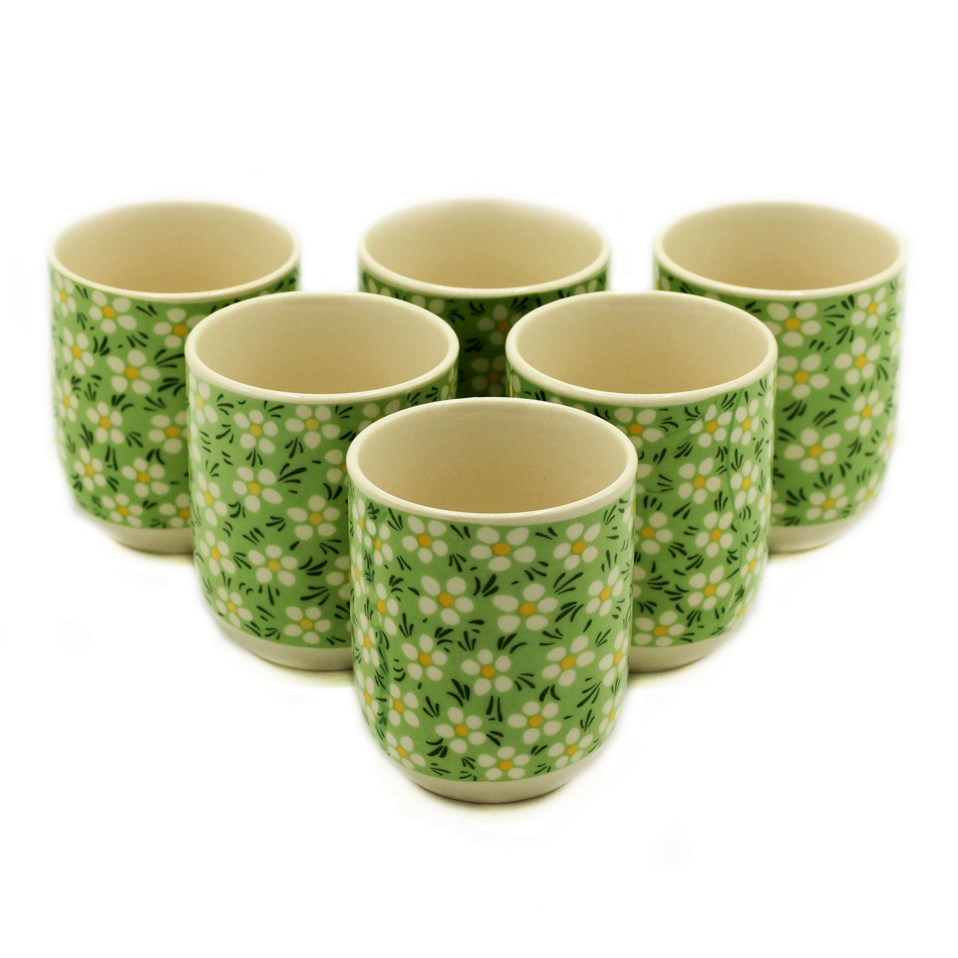 Petite green ceramic tea cups with a delicate white daisy pattern and a handleless, rounded design.