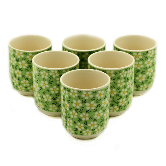 Petite green ceramic tea cups with a delicate white daisy pattern and a handleless, rounded design.
