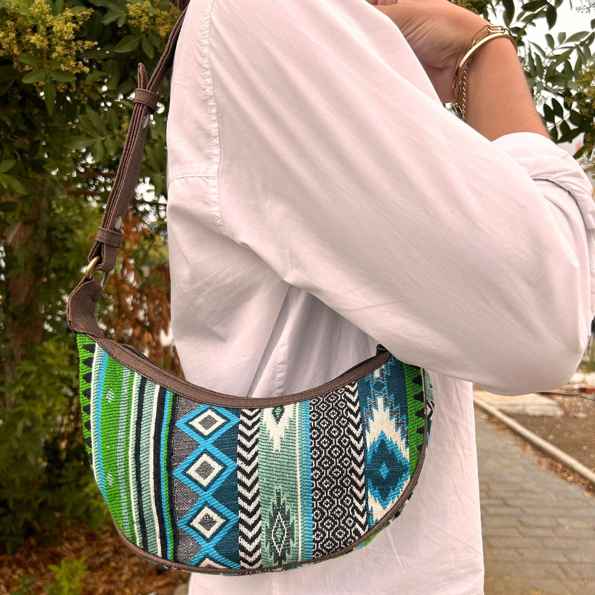 Close-up of a vibrant green patterned jacquard hobo bag with a textured fabric and a dark brown shoulder strap.
