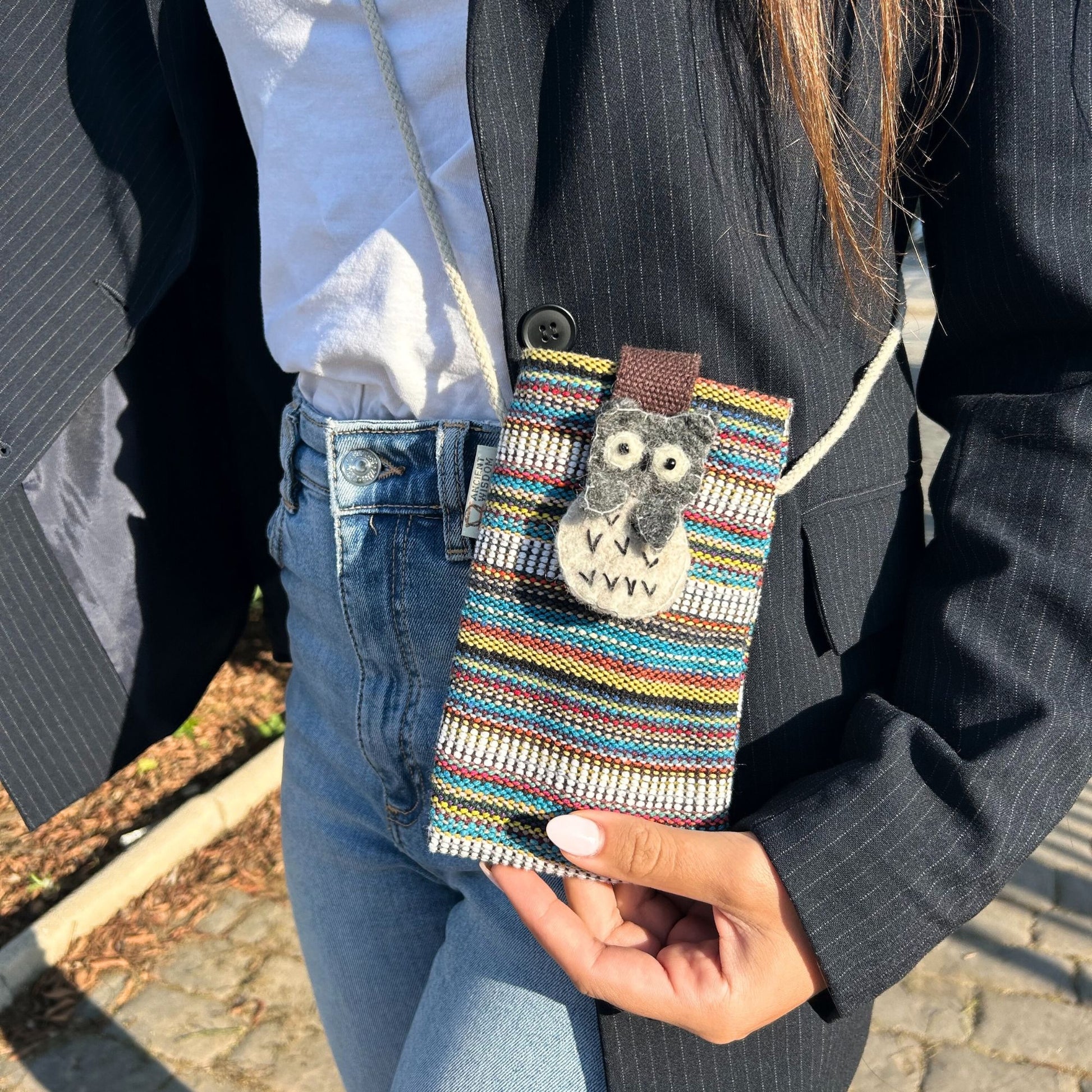 Handmade phone holder bag with vibrant multi-coloured stripes, white accents, and a charming owl decorative patch.
