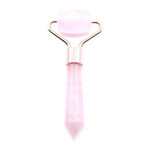 Small light pink rose quartz gemstone face roller with a silver-toned metal handle on a plain background.