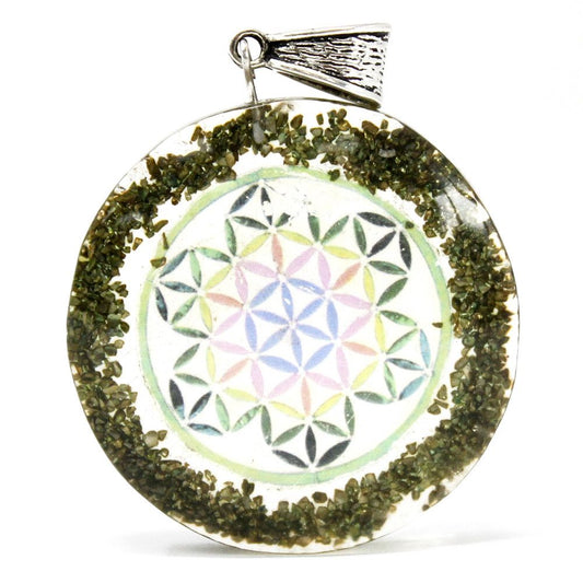 Circular orgonite pendant featuring green gemstone chips, copper metal filings, and an esoteric mandala symbol.