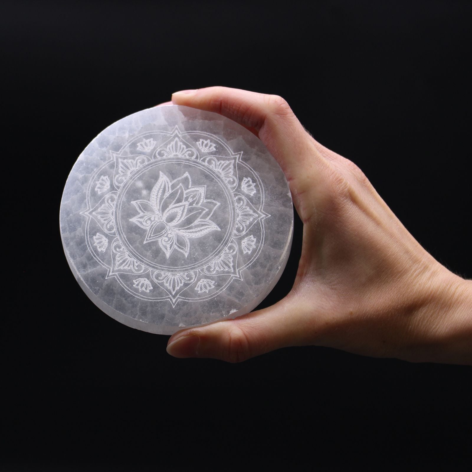Round white selenite charging plate engraved with an intricate lotus mandala design.