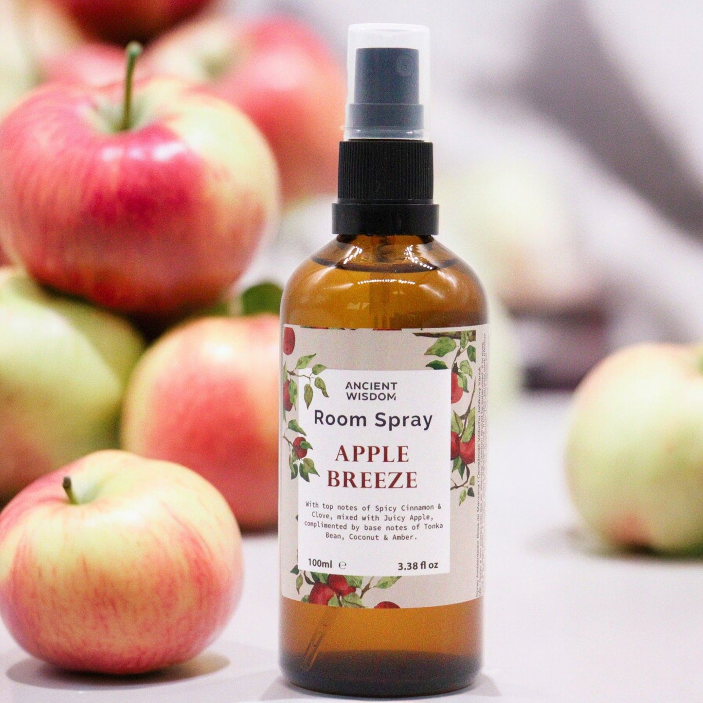 100ml amber glass bottle of Apple Breeze room spray with a black spray nozzle on a plain background.