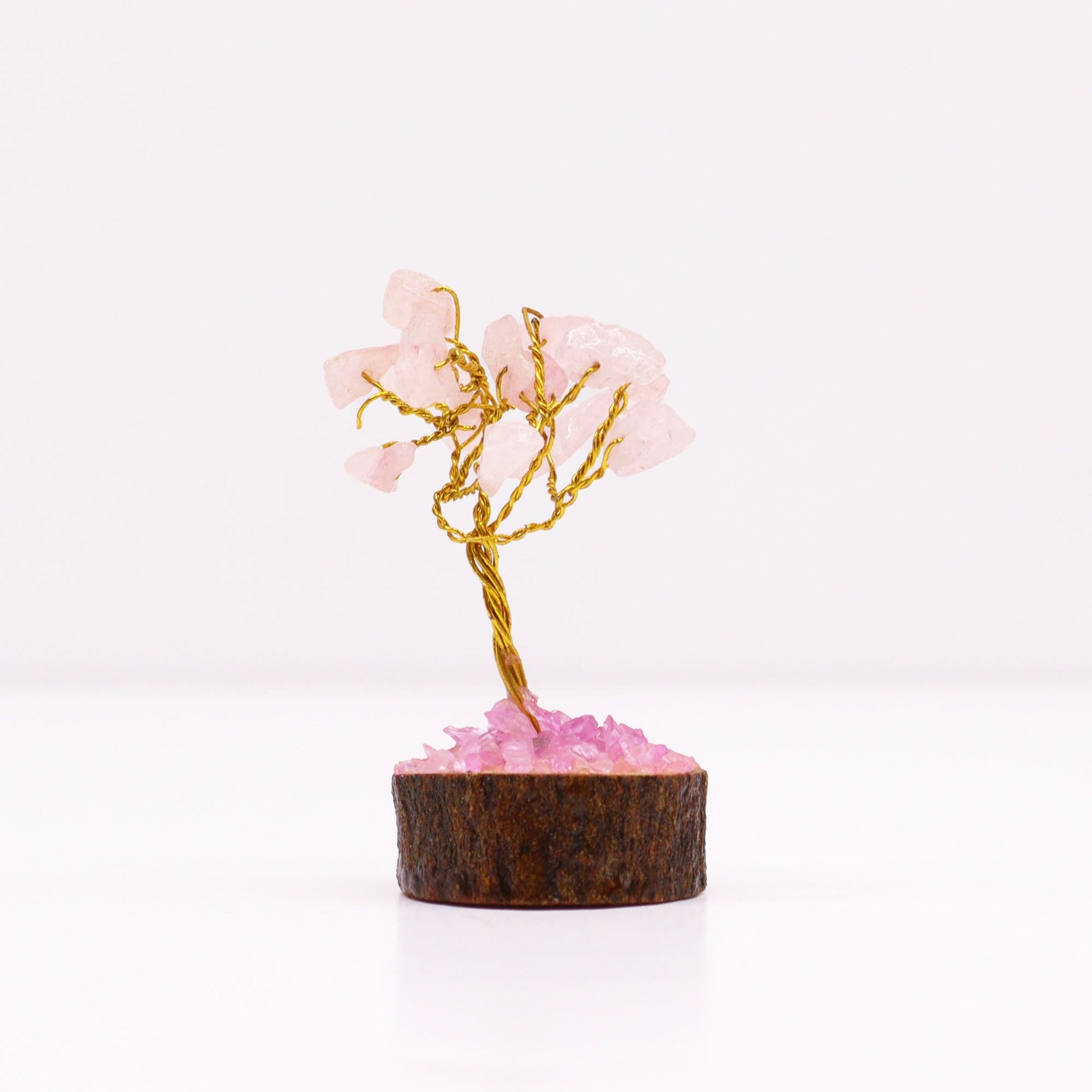 Miniature gemstone tree with delicate pink rose quartz leaves on a natural wood base.