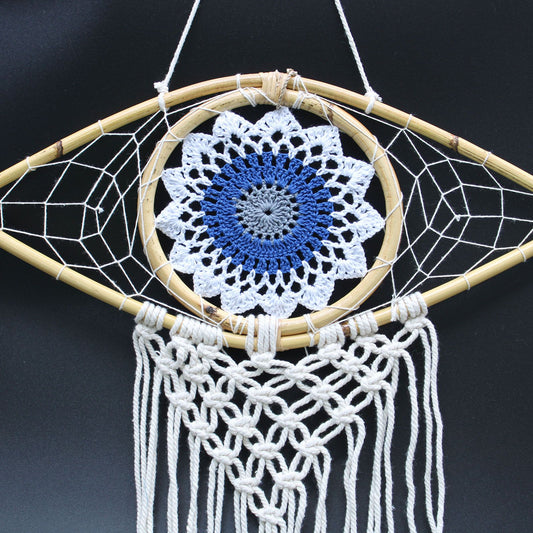 Intricate white macrame dream catcher featuring a blue and grey evil eye symbol in the centre with hanging tassels.