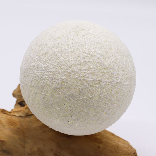 Elegant ivory cotton thread lamp shade resting on a unique, naturally shaped Indonesian driftwood base.