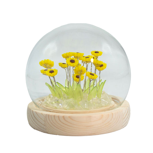 Delicate sunflower arrangement with soft LED lights inside a clear glass dome on a natural wooden base.