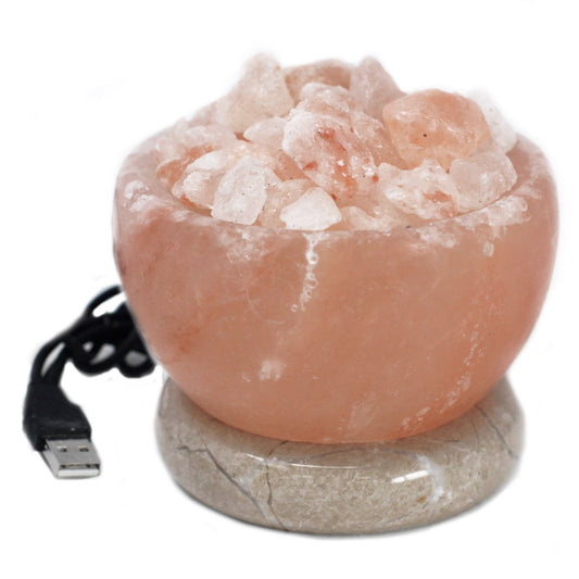 A glowing crystal salt lamp bowl filled with raw salt chunks, emitting a vibrant multi-coloured light from within.