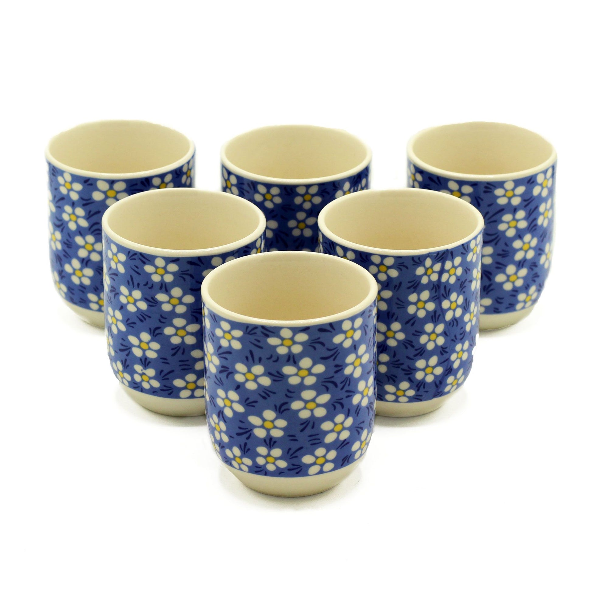 Elegant white ceramic tea cups featuring a delicate blue daisy floral pattern and matching saucers.