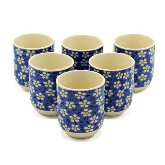 Elegant white ceramic tea cups featuring a delicate blue daisy floral pattern and matching saucers.
