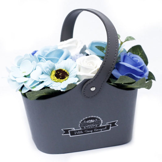 Petite wicker basket filled with realistic blue and white soap flower roses and greenery.